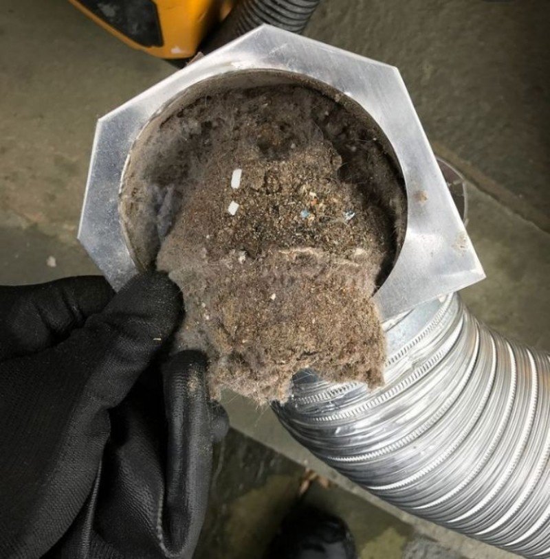 Technician cleaning a return air vent grille in a Brooklyn home